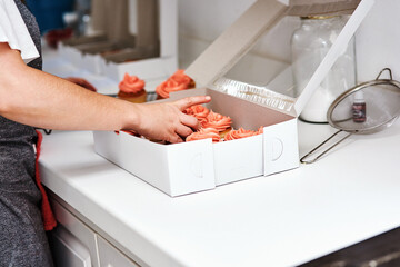 Bakery, box and person with cupcake for birthday or packaging order in kitchen of restaurant....
