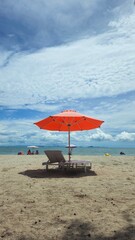 Beautiful tropical scenery, two sun beds and orange umbrella. White sand, blue sky clouds at Mui Nai beach, Ha Tien, Vietnam in summer.