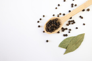 dried bay leaf and black pepper on a white background.