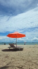 Beautiful tropical scenery, two sun beds and orange umbrella. White sand, blue sky clouds at Mui Nai beach, Ha Tien, Vietnam in summer.