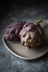 Obraz premium Fresh purple artichokes on dark background 