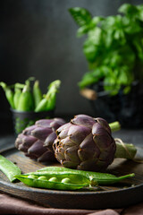 Fototapeta premium Fresh purple artichokes on dark background 
