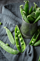 Fresh green peas on the table in a grey pot on dark background 