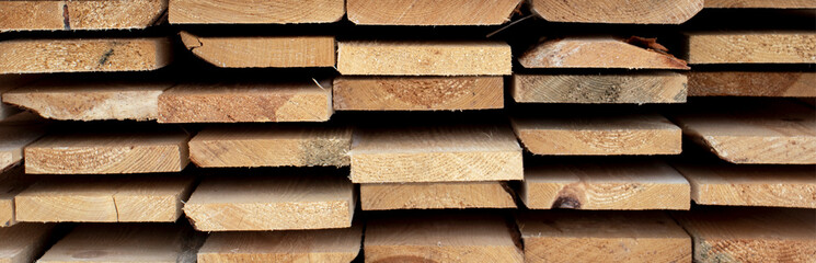 Roughly processed boards lie in a stack. Close-up view of the ends of the boards. Softwood lumber...