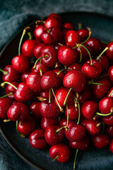 Fresh red cherries on the plate on dark background 