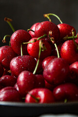 Fresh red cherries on the plate on dark background 