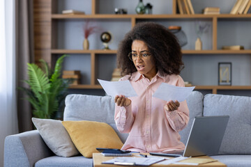 Upset and distressed woman working with documents and papers at home, paying utility bills and loan...