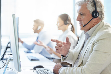 Mature, man and call center with headphone for conversation and communication in workplace. Group,...
