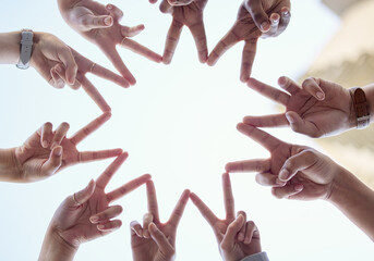Hands, sky and people with finger stars for synergy or unity above with teamwork, low angle and diversity. Group, shape and sign for solidarity with collaboration, community and huddle with peace.