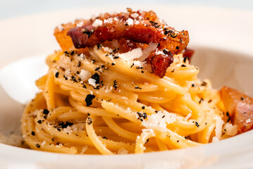 Piatto di saporiti spaghetti alla gricia, tipica ricetta di pasta condita con pecorino, guanciale e...