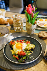 Avocado toast with fried eggs and vegetables on a brunch table