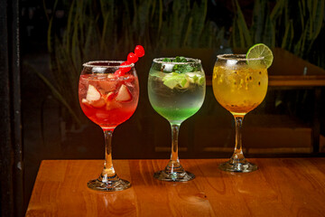 Italian soda, coctails, passion fruit, apple and strawberry on glass cups black background