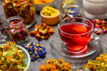 Assortment of dry herbal and berry tea and a cup of tea on a wooden background.Medicinal Healing herbs.Alternative medicine concept.Linden, calendula, cornflowers, marigold, tansy, tea rose.dry herbal