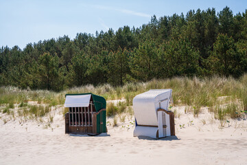 On the sandy beach there are two strandkorbs facing in different directions. Protection from wind...