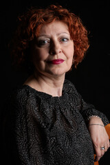 Elegant red-haired woman on black background