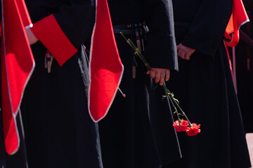 Cossacks in uniform lay flowers. Carnation flower in hand. A red carnation flower in the hands of a Cossack warrior.
