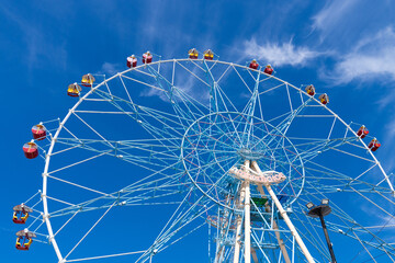 Fototapeta premium Ferris wheel against the blue sky. Modern Ferris wheel. Big, tall white Ferris wheel in front of a perfect blue sky. Happy summer vacation feelings. Sochi Ferris wheel 