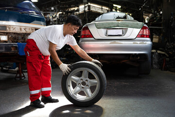 mechanic holding and pushing a tire for fixing in garage