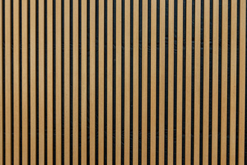 A wall of vertical wooden strips in warm colour, interior decoration background. 