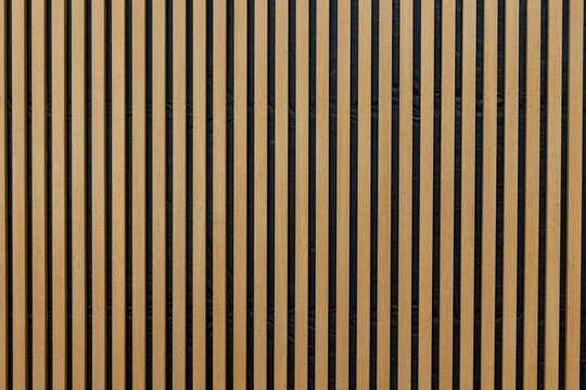 A wall of vertical wooden strips in warm colour, interior decoration background. 