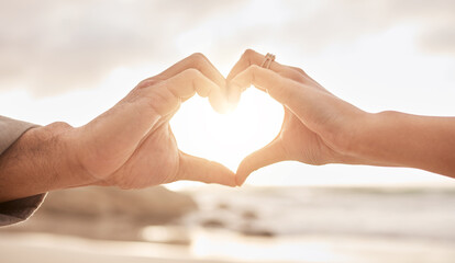 Couple, hands and heart by sunset with love on beach for honeymoon or vacation in summer with...