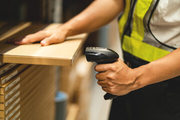 A man in a white shirt and yellow vest is looking at a shelf with a barcode scanner