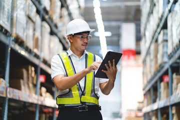 A man in a safety vest is using a tablet to point at something in a warehouse. Concept of...