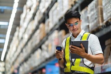 A man wearing a safety vest and glasses is standing in a warehouse, holding a tablet and a barcode...