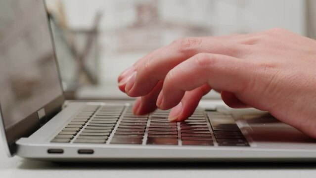 Young woman is typing on computer keyboard close-up. Modern work office place concept. Working and chatting in personal laptop