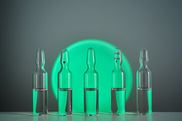 Several ampoules for injection with medicines on a green background.