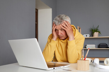 Sad upset tired senior man at home working on laptop having lots task being overworked massaging...