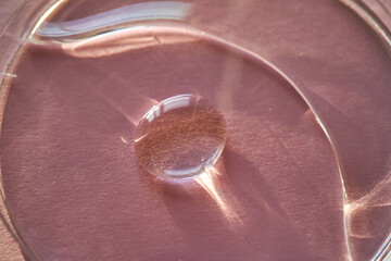Beautiful volumetric drop of cosmetic product on a pink background.