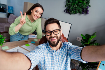 Photo of two people workers make selfie girl show v sign in modern workstation workplace