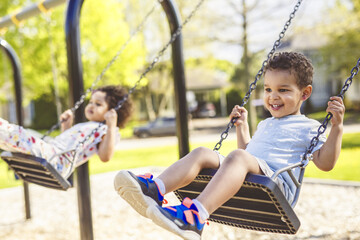 Happy child brother and sister on a swing. Happy kid on playground