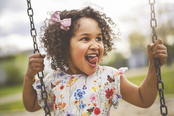 Happy 3 years old girl on a swing. Happy kid on playground