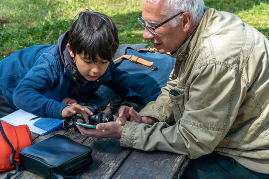 Grandfather teaching photography to grandson in park