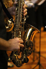 Obraz premium Musician playing the saxophone at a classical music concert. Close-up of person's hands playing the saxophone. Wind musical instrument.