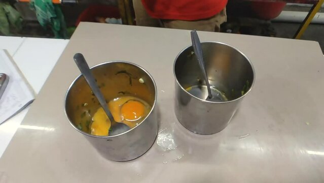 High angle shot of hands cracking the eggs into stainless steel containers in slow motion, adding some of salt. Preparing to cook an omelette. Perfect for culinary projects or tutorials