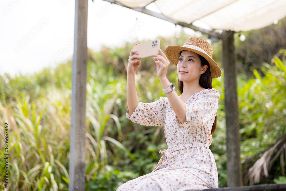 Wall mural woman with straw hat and use mobile phone to take photo at outdoor