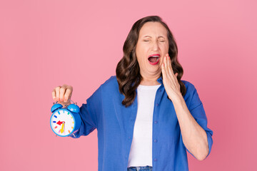 Photo portrait of nice pensioner female yawn hold clock sleepy wear trendy blue outfit isolated on...