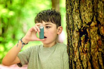 boy has an asthmatic agent in his hands in the park backgrounds. The boy in the white T-shirt with...