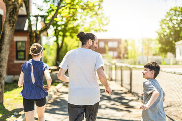 A father and two childs exercising and jogging together at an outdoor park having great fun
