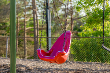 Accessible swing, chair, in a typical elementary school, municipal park, playground with engineered wood fiber safety fall surface.	