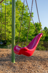 Accessible swing, chair, in a typical elementary school, municipal park, playground with engineered wood fiber safety fall surface.	