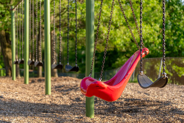 Accessible swing, chair, in a typical elementary school, municipal park, playground with engineered wood fiber safety fall surface.	