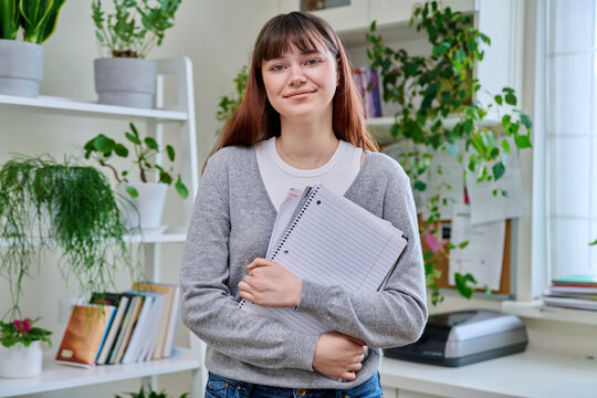 Portrait of smiling female student, 19,20 years old, looking at camera, in home interior