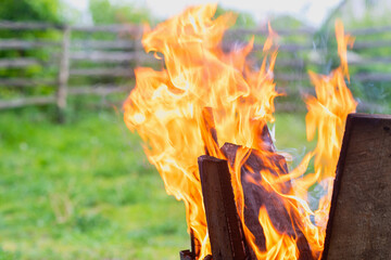 Burning firewood on a blurred grass background.