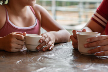 detailed shot of the hands of two girls holding a cup of tea or coffee in their hands