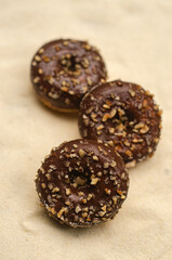 Three chocolate donut with sprinkles on beige background . High quality photo