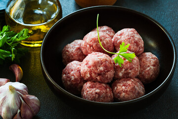 Raw ground meat meatballs in black bowl